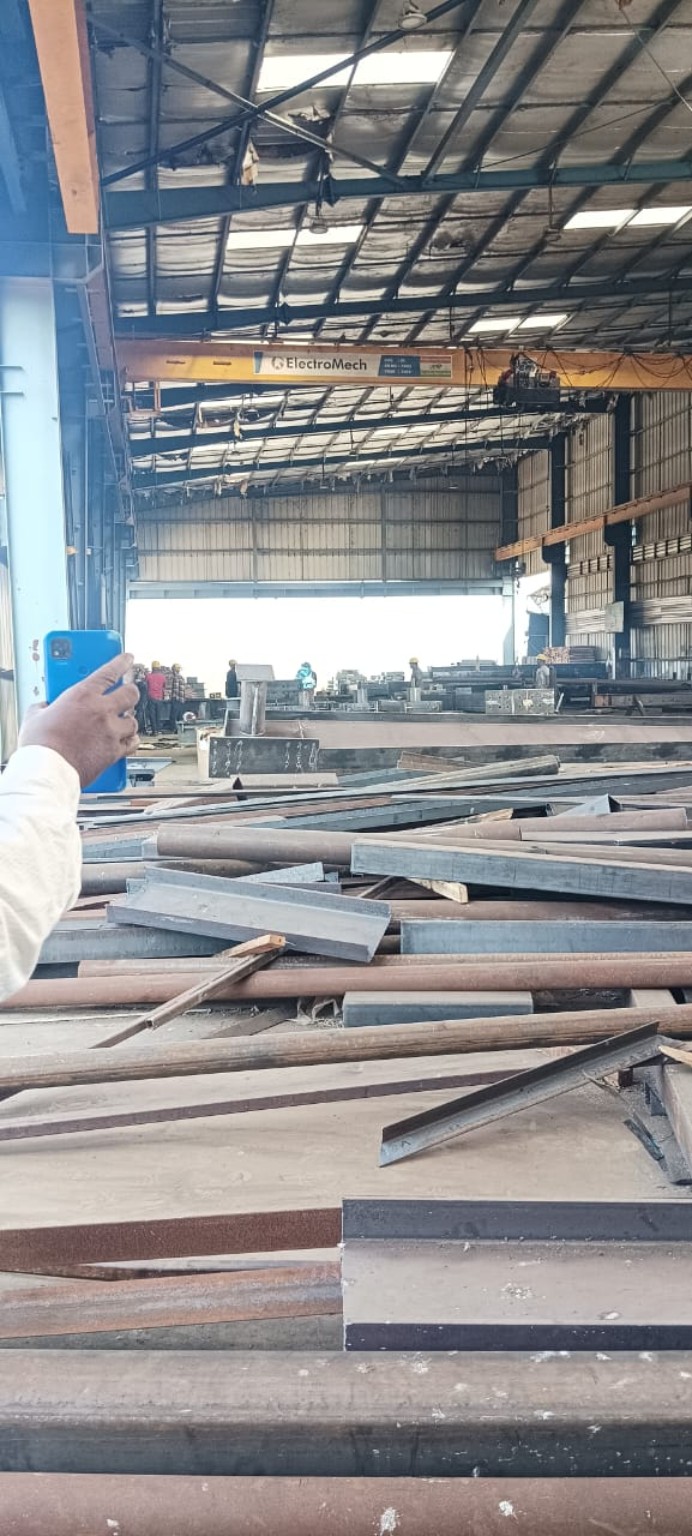 Supplied workshop photograph showing structural steel members and an overhead crane.