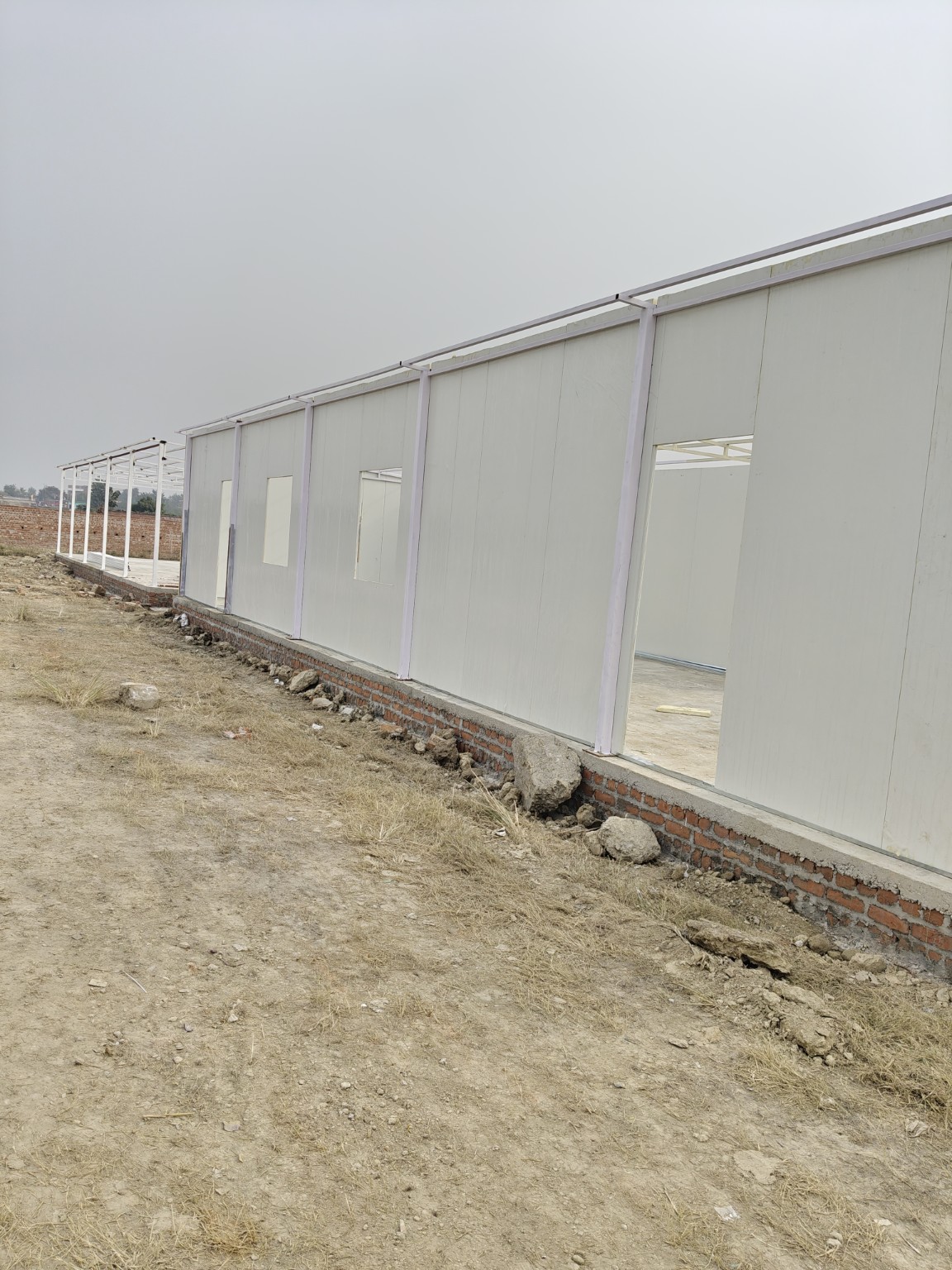 Exterior of a prefabricated panel building under construction with door and window openings.
